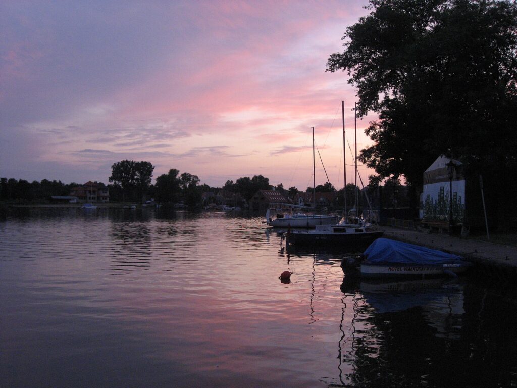 Sunset over a calm Masurian lake with sailing boats moored in Mikołajki